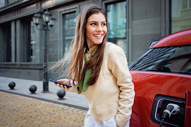 Portrait of woman charging her electric car